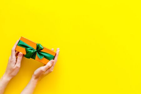box for gifts in hands on yellow background top view mock upの写真素材