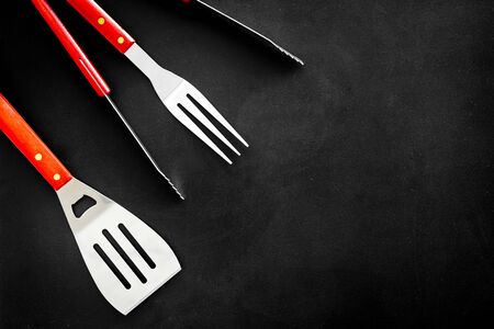 Tongs, fork, spatula for barbecue and grill on black background top view copyspaceの写真素材