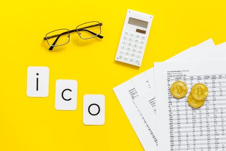 ICO with coins and calculation table on office desk yellow background top viewの写真素材