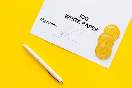 White paper ICO, coins, pen on yellow background top viewの写真素材