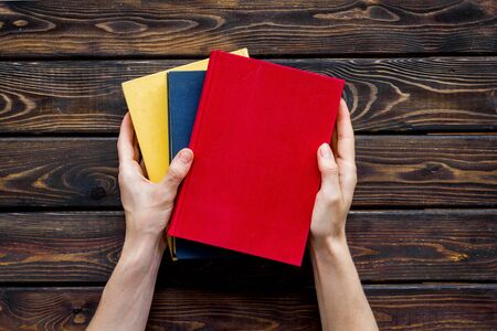 Book in hands for reading and education on wooden background flatlay mock-upの写真素材