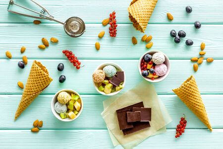 summer dessert with ice cream, cones, chocolate, berries and nuts on mint green wooden backgroung top viewの写真素材