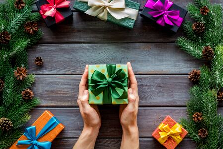 Frame from spruce and gift in hands for new year on wooden background top veiwの写真素材