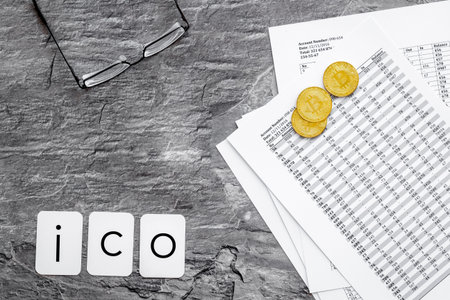 ICO with coins and calculation table on office desk gray textured background top view
