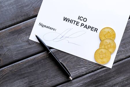 Initial coin offering ICO white paper, bitcoin, pen on gray wooden background top viewの写真素材