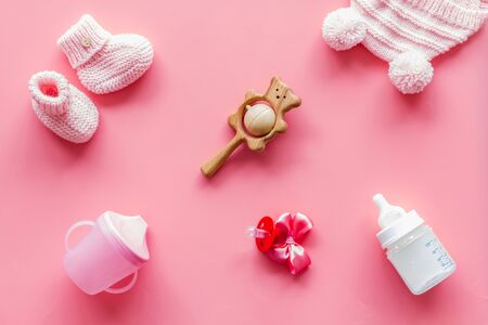 Cute baby clothes for girl, rattle, bottle and dummy on pink background top viewの写真素材