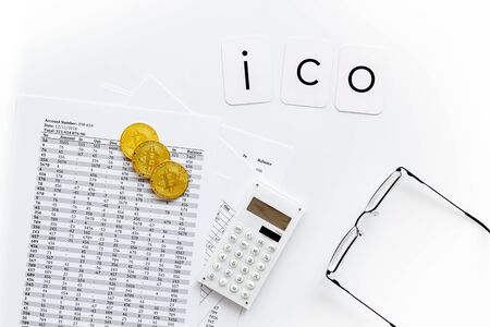Initial coin offering ICO with coins, calculation table, office tools on white background top viewの写真素材