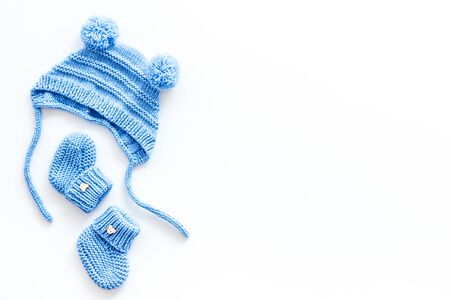 Booties and hat for newborn boy on white background top view mockup