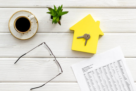 Calculate taxes for house with figure, keys, table, glasses and coffee on white wooden background top viewの写真素材