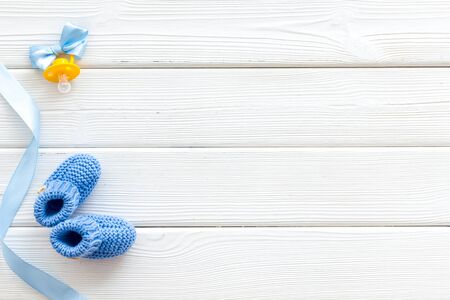 Blue knitted footwear and dummy for baby boy on white wooden background top view mockupの写真素材