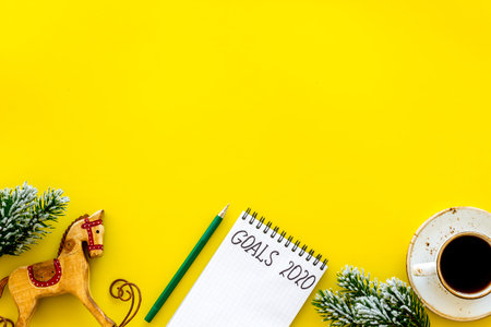 Planning New Year 2020. Notebook with goals on yellow background top view space for text