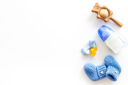 Cute baby clothes for boy, rattle, bottle and dummy on white background top view copyspace