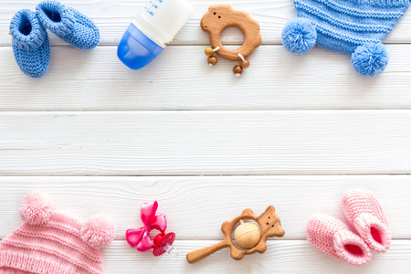 Blue and pink knitted footwear, hat, dummy, rattle and bottle frame for baby boy and girl on white...
