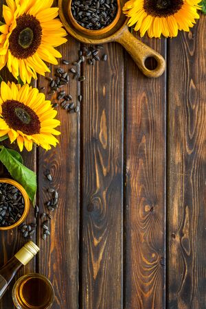 Field flowers. Frame of sunflowers, oil and seeds on wooden background top view mockupの写真素材