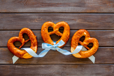 Octoberfest symbol. Fresh bavarian pretzels on dark wooden background top view