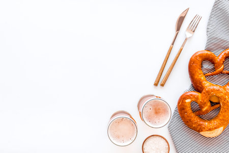 Octoberfest table background. Pretzels and beer glasses on white background top view space for text...