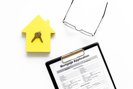 Mortgage application with glasses, house figure and keys on white background top viewの写真素材