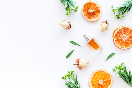 Composition with perfume, dry oranges and flowers on white background top view copy space frame