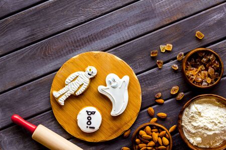 Cooking halloween cookies in shape of spooky figures, rollin pin, nuts and flour on wooden background top view mockupの写真素材