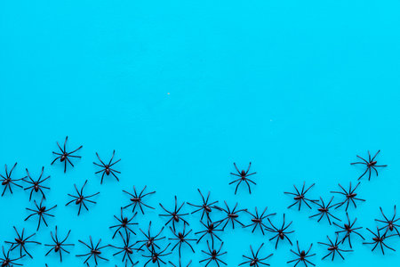 Minimalistic Halloween frame with small spiders on blue background top view copy space