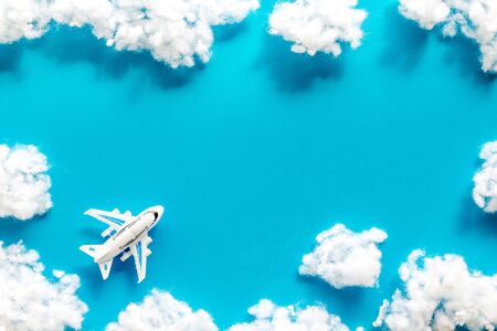 Fly by plane concept. Airplane model and clouds on blue background top view frame copy spaceの写真素材