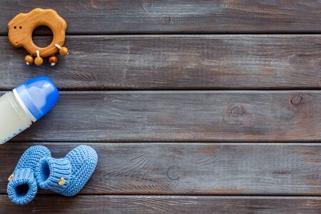 Booties for newborn boy with rattle and bottle on wooden background top view mock up