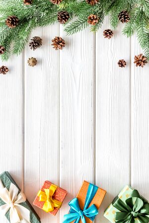Presents for christmas in boxes and spruce frame on white wooden background top veiw copyspaceの写真素材
