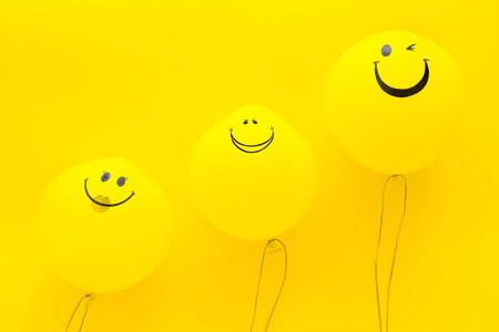 Happiness emotion. Yellow balloon with smile on yellow background top view copy spaceの写真素材