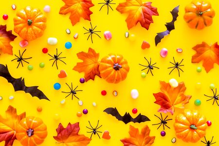 Bright Halloween composition with sweets, bats and pumpkins on yellow background top view patternの写真素材