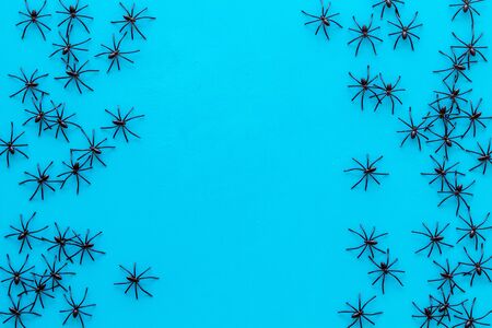 Minimalistic Halloween frame with small spiders on blue background top view copy space