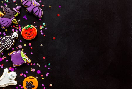 Celebration halloween and party decorations. Creepy cookies for halloween treat frame on black background top view mockupの写真素材