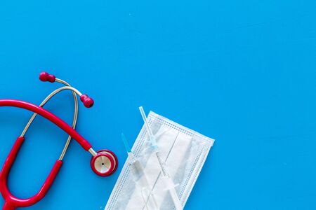 Medical background with face mask, stethoscope, vaccine on blue background top view copy spaceの写真素材