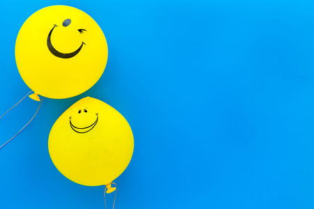Happiness emotion. Yellow balloon with smile on blue background top view.