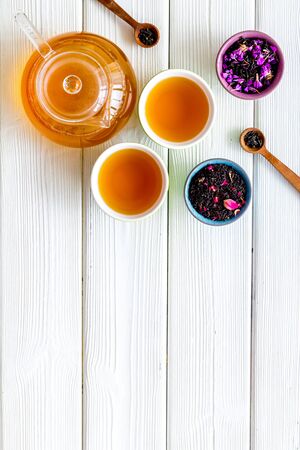 Tea in pot and cups with dry leaves on white wooden background top view mock up.の写真素材