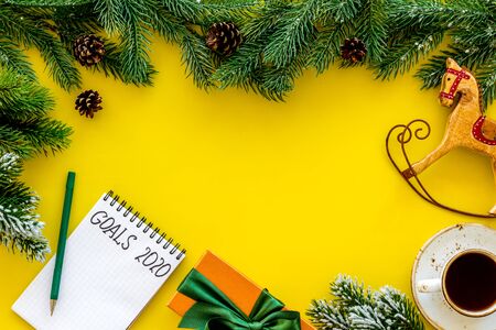Planning New Year 2020. Notebook with goals on yellow background top view copy space mockup