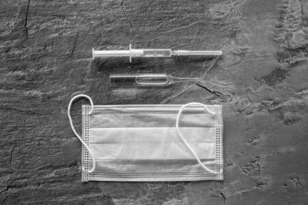 Influenza preventive tools. Medical face mask and vaccine on grey background top view copy spaceの写真素材