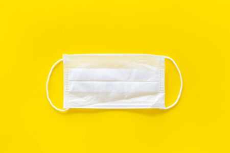 Flu prevention concept. Medical face mask on yellow background top view copy spaceの写真素材