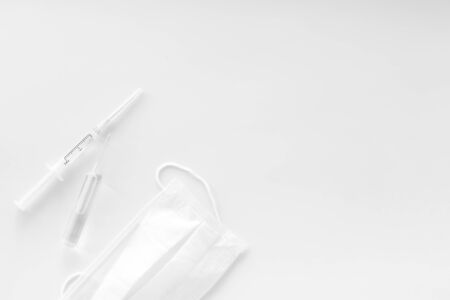 Influenza preventive tools. Medical face mask and vaccine on white background top view copy spaceの写真素材