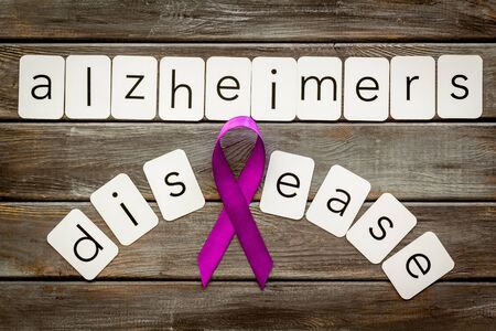 Alzheimers disease text near violet ribbon on dark wooden background top viewの写真素材