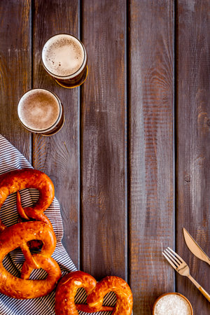 Octoberfest table background. Pretzels and beer glasses on dark wooden background top view frame...