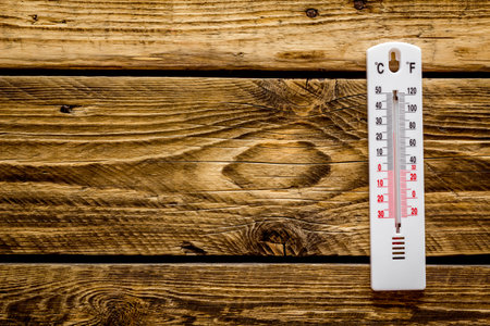 Weather thermometer on dark wooden background top view.