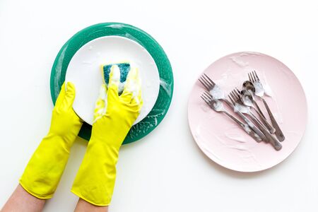 Washing dishes. Hands in rubber gloves and plates on white background top view.の写真素材