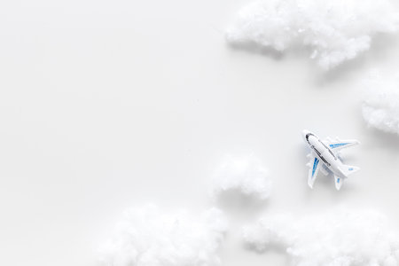 Travelling background. Fly by plane concept. Airplane model and clouds on white background top view.