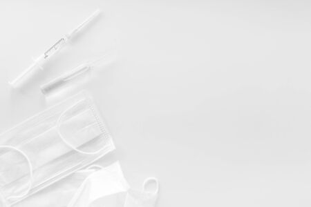 Influenza preventive tools. Medical face mask and vaccine on white background top view space for textの写真素材
