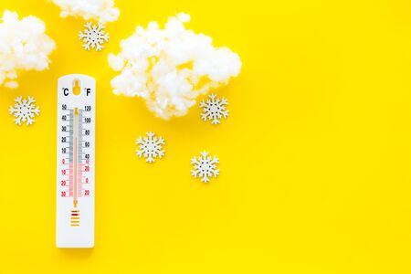 Its snowing concept. Snow and thermometer on yellow background top view copy spaceの写真素材