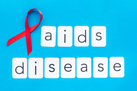 AIDS disease text near red ribbon on blue background top view