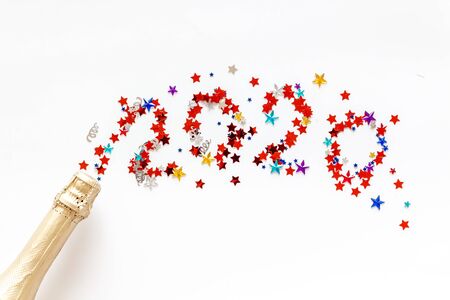 Celebrate New Year 2020. Date on confetti near champagne bottle on white background top view copy spaceの写真素材