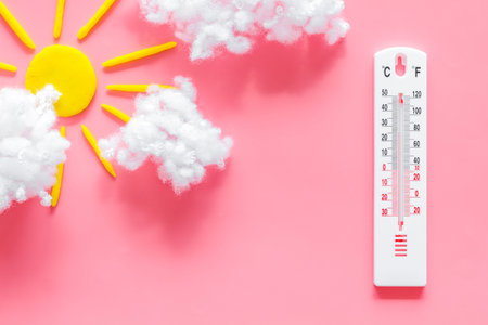 Cloudly weather concept. Sun and clouds on pink background top view space for text