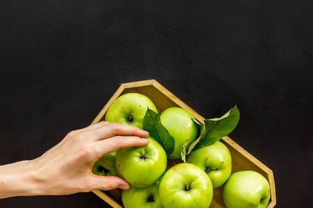Healthy diet concept. Fresh apples in tray, hand hold apple, black background top view copy spaceの写真素材