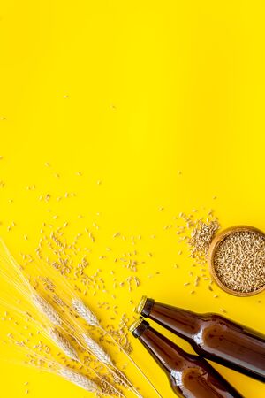 Beer ingredients. Barley near beer bottles on yellow background top view.の写真素材